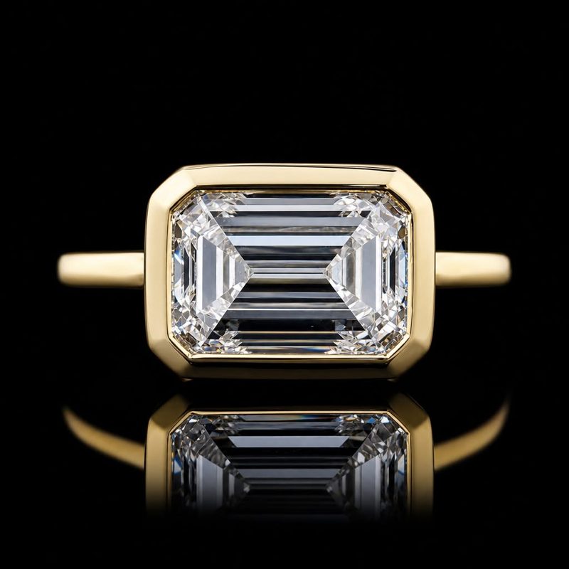 Rectangular step-cut center stone in a yellow-metal bezel ring
