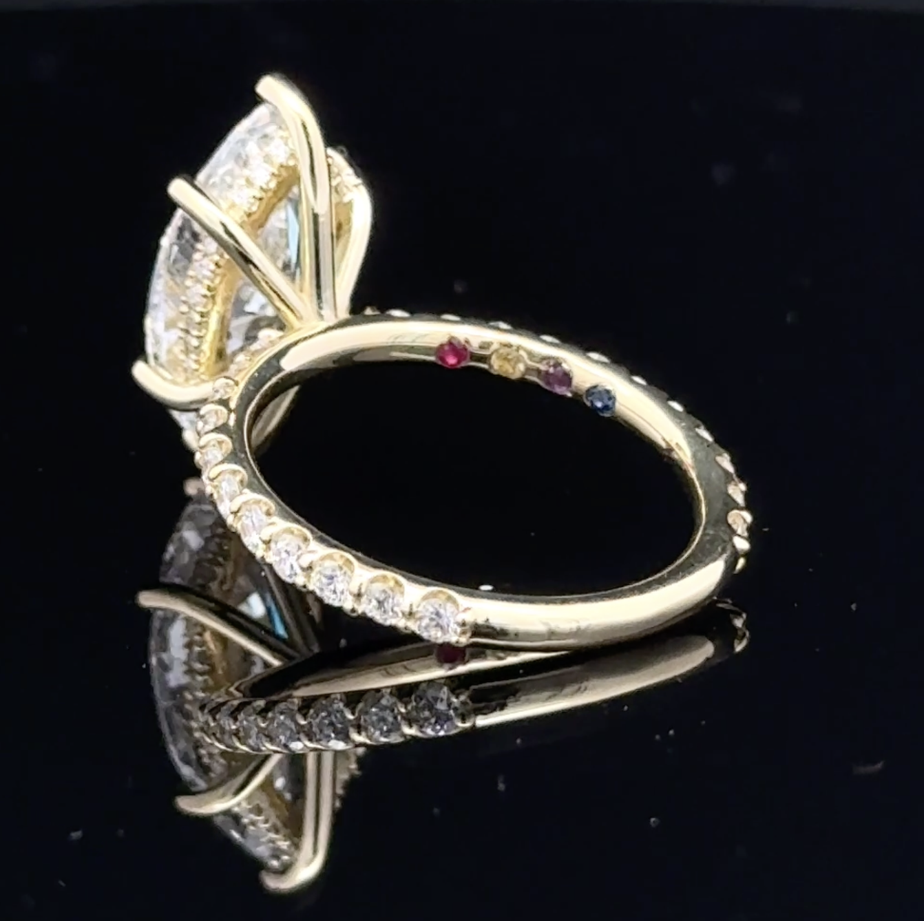Four colored family stones inside an 18k yellow gold marquise engagement ring.